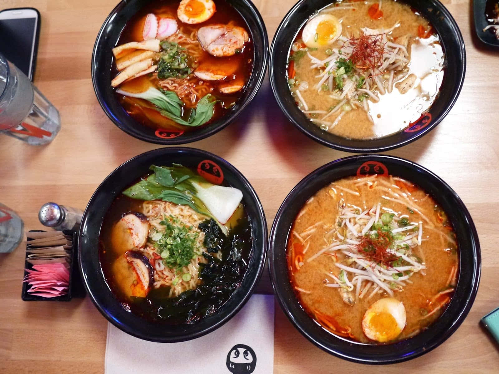 Noodles 桌布 壁紙 — 四碗熱騰騰的拉麵，配上溏心蛋、豆芽和青菜，誘人地放在木桌上。