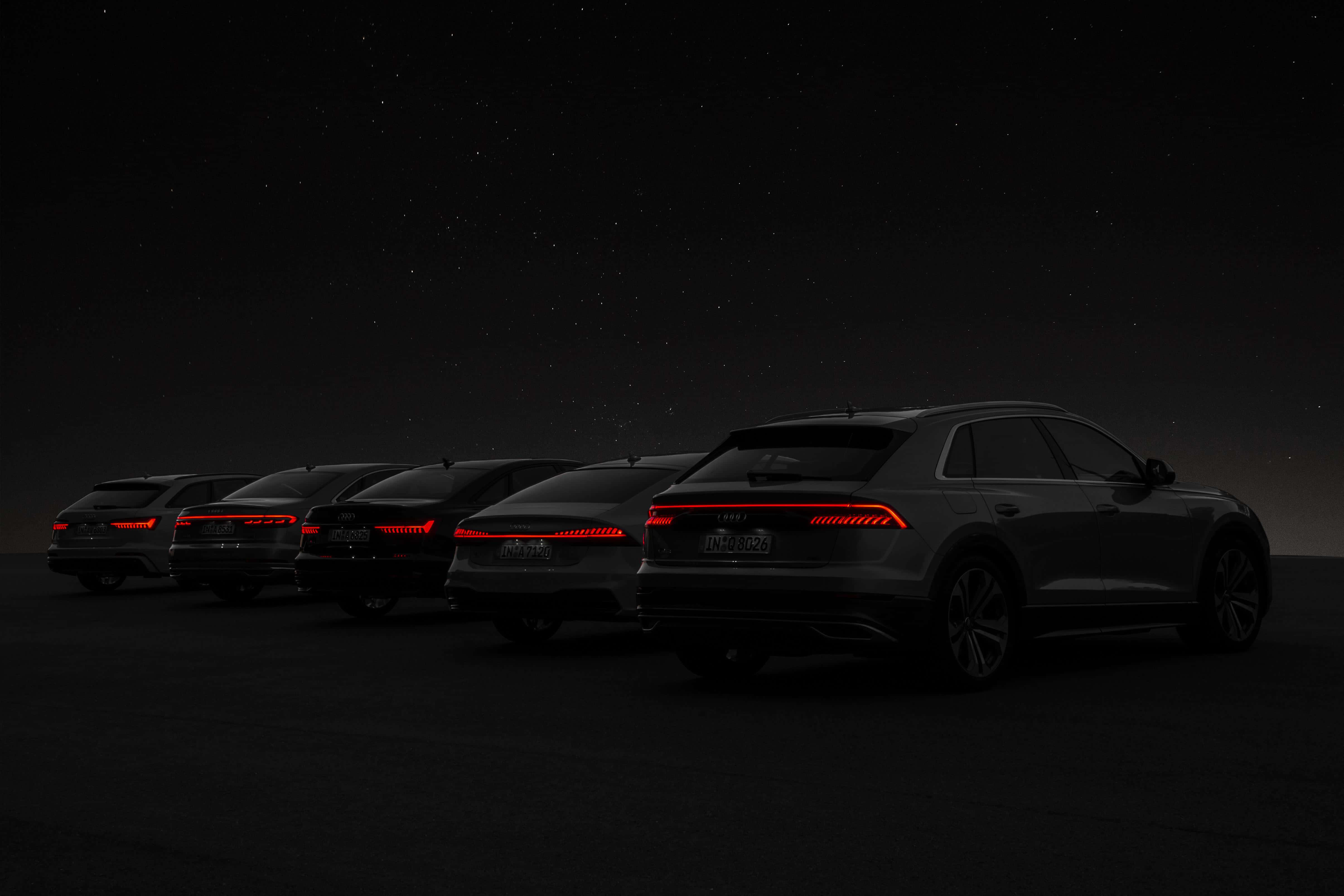Black Car 4K 桌布 壁紙 — 四輛時尚黑色SUV在繁星點點的夜空下排列，紅色尾燈閃爍發光。