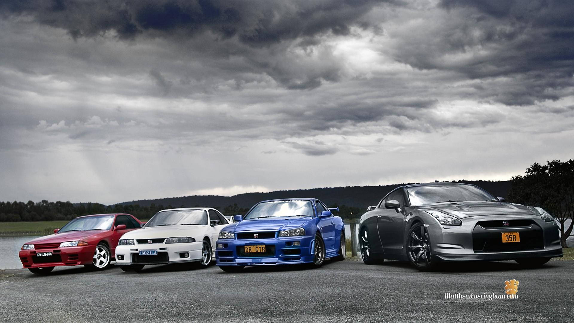 四輛日產Skyline GT-R跑車停在瀝青路上，上方是暴風雨的天空。 — Toyota Supra Mk4 壁紙