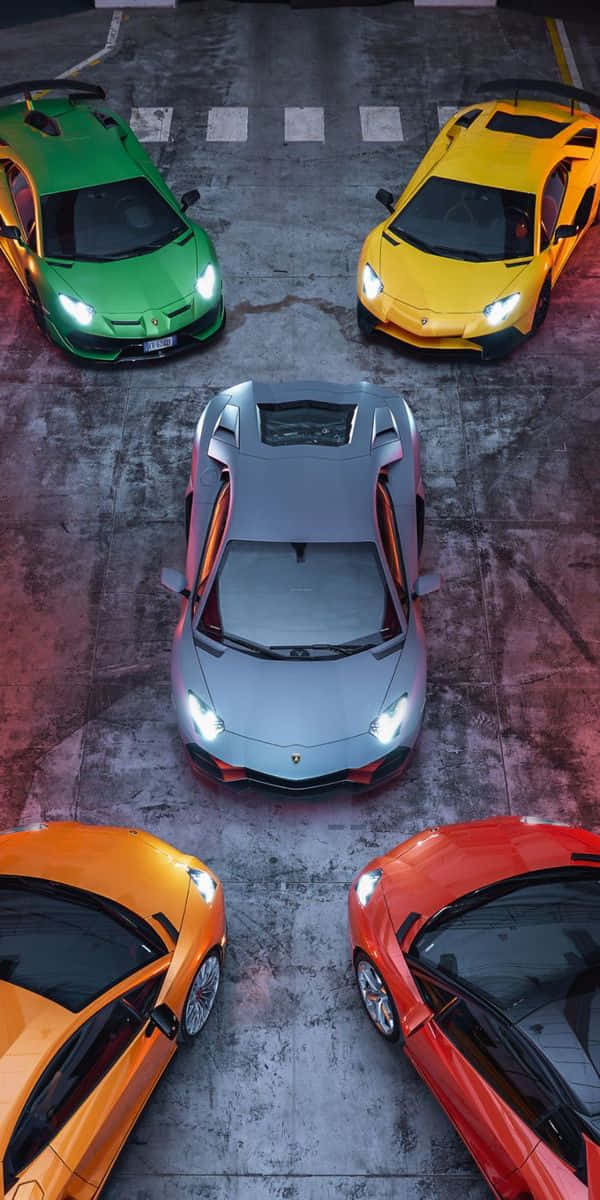 race car 桌布 壁紙 — 四輛色彩鮮豔的藍寶堅尼超級跑車在戲劇性燈光下停泊在混凝土停車場。