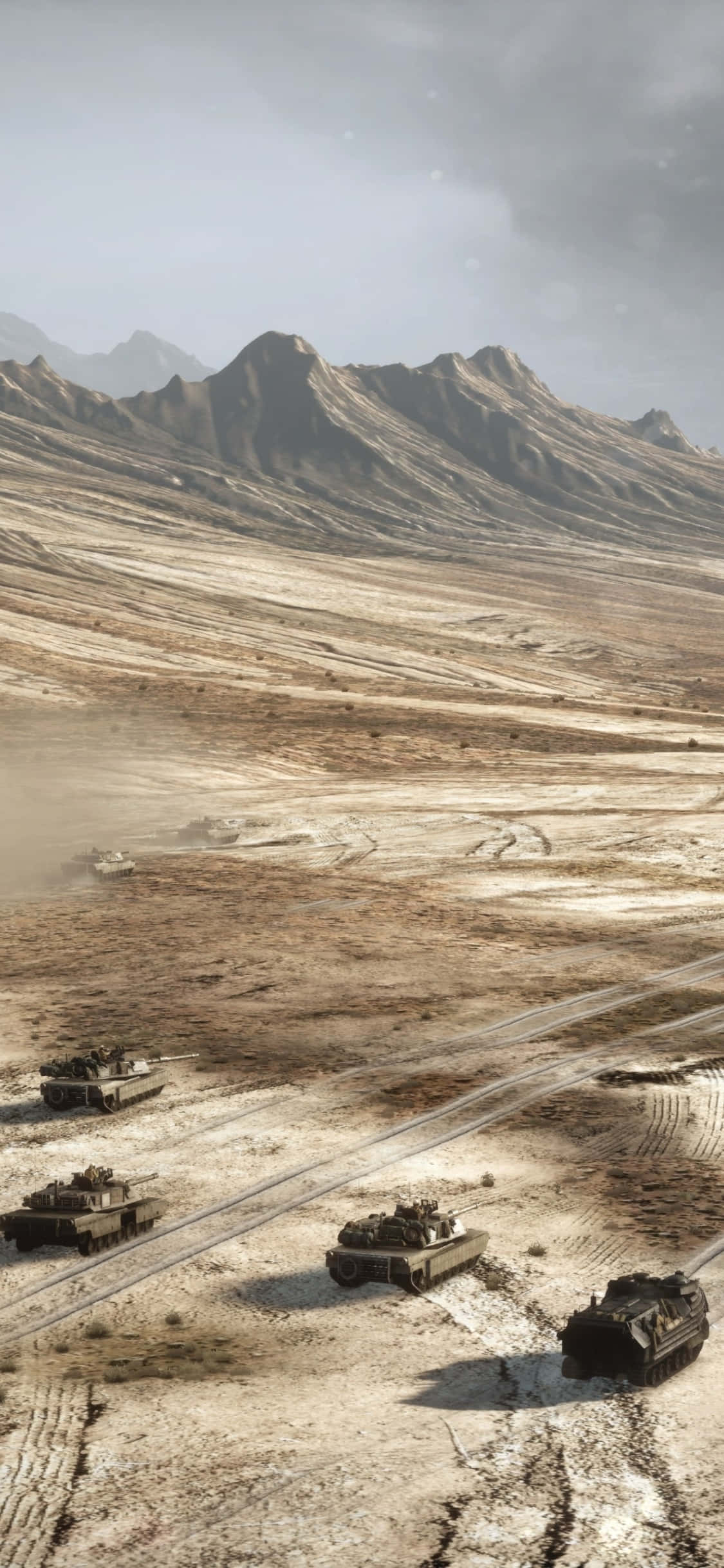 iPhone Xs Battlefield 3 桌布 壁紙 — 四輛軍用坦克在一片荒蕪的沙漠山谷中前進，崎嶇的山脈在朦朧的天空下矗立。