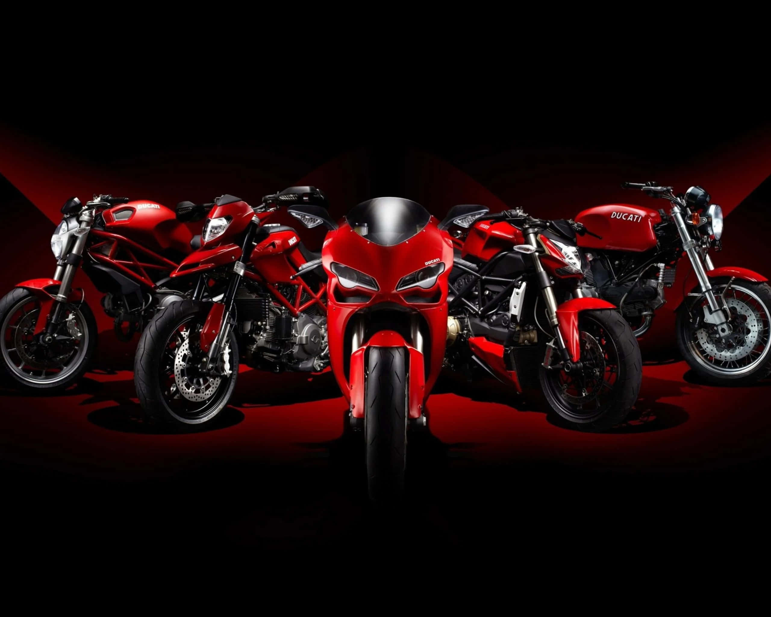 機車 桌布 壁紙 — 四輛閃亮的紅色Ducati摩托車在黑色背景上以紅色聚光燈戲劇性地照亮。