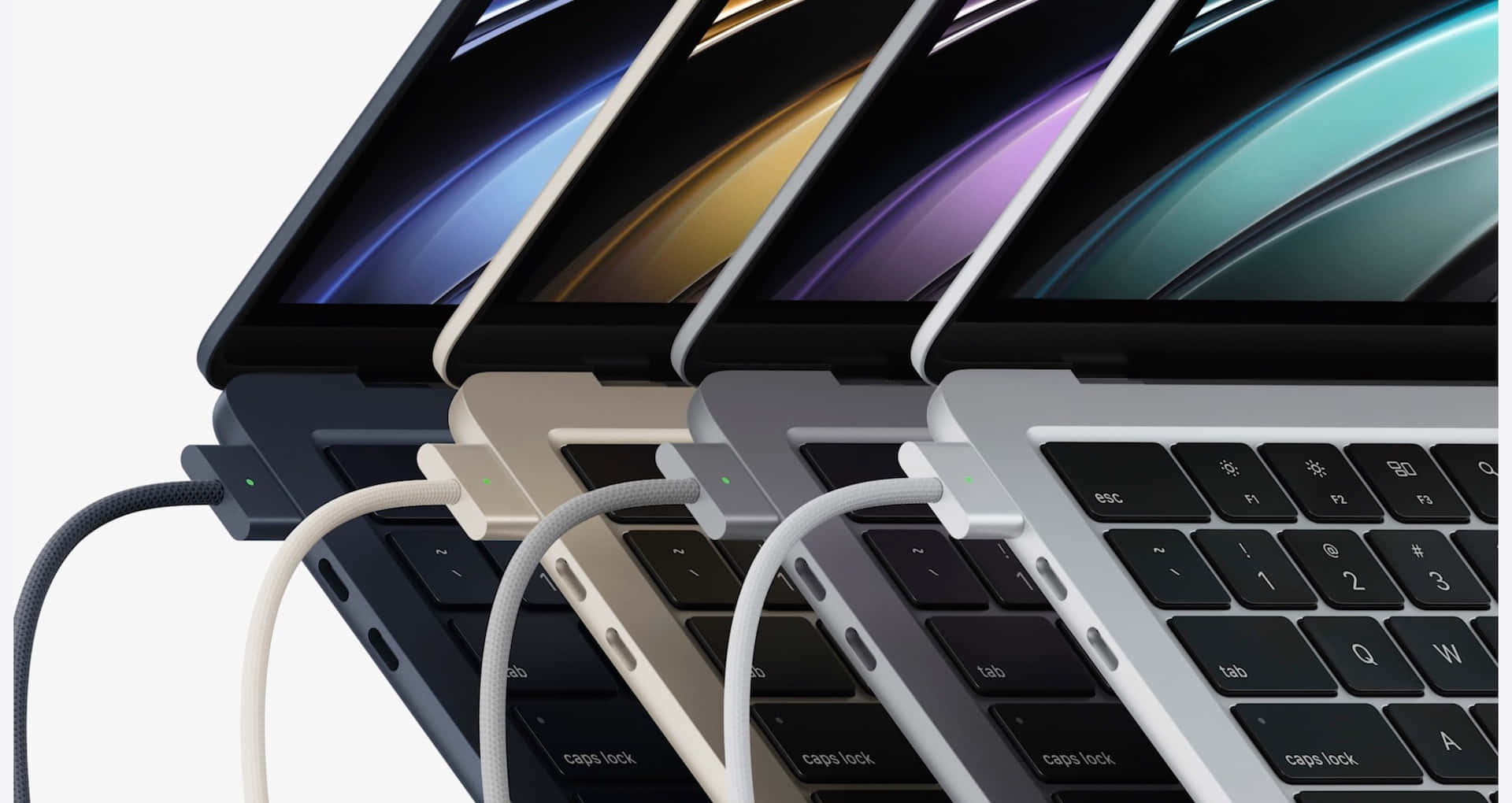 MacBook 動態圖片 桌布 壁紙 — 四部太空灰、銀色、金色和午夜黑色的 MacBook Pro 以對角線傾斜放置，帶有彩色漸變螢幕和已插入的充電線。