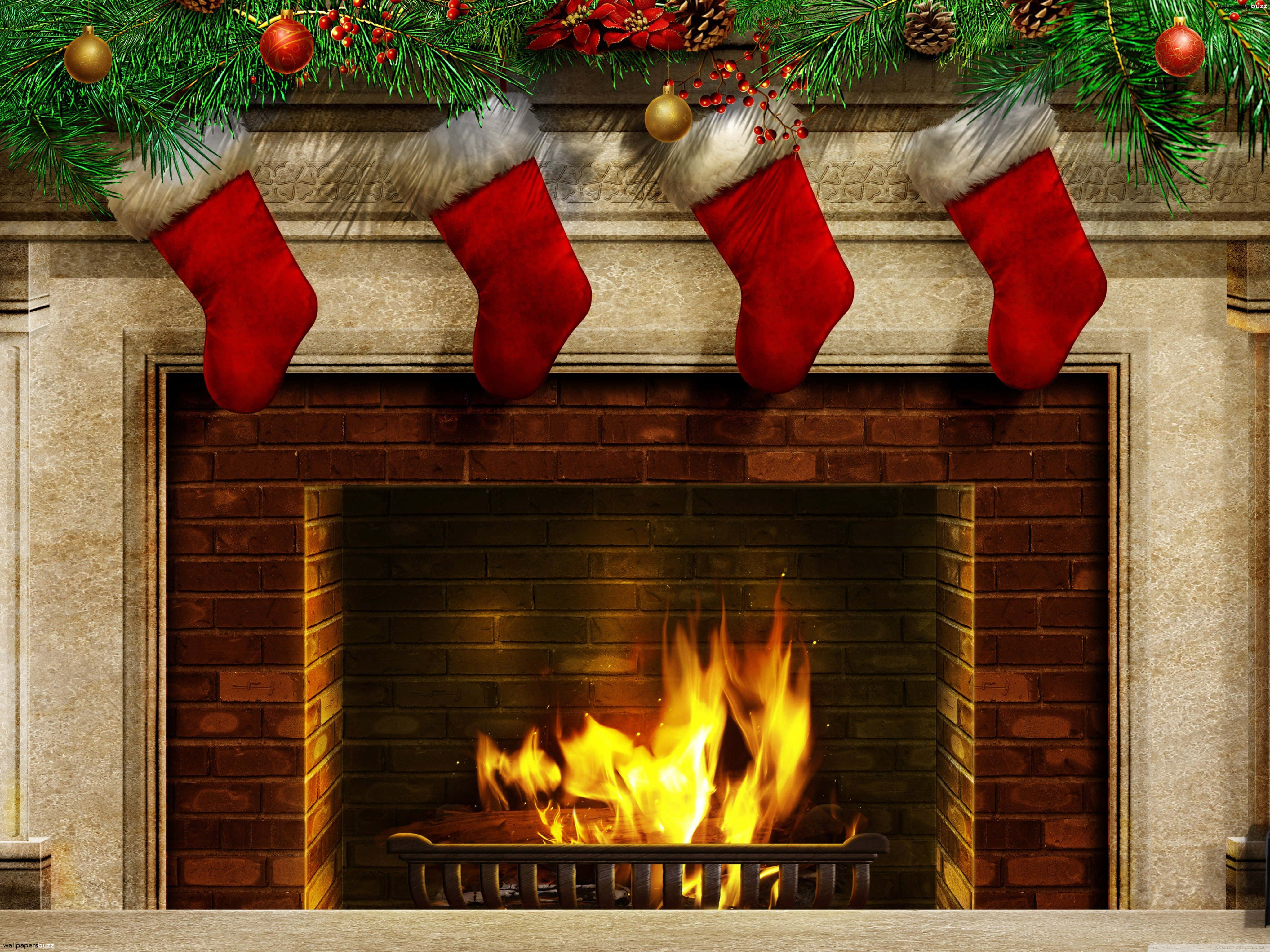 Christmas Decor 桌布 壁紙 — 四隻紅色聖誕襪掛在一個燃燒的磚砌壁爐上方，壁爐飾有松樹花環和裝飾品。
