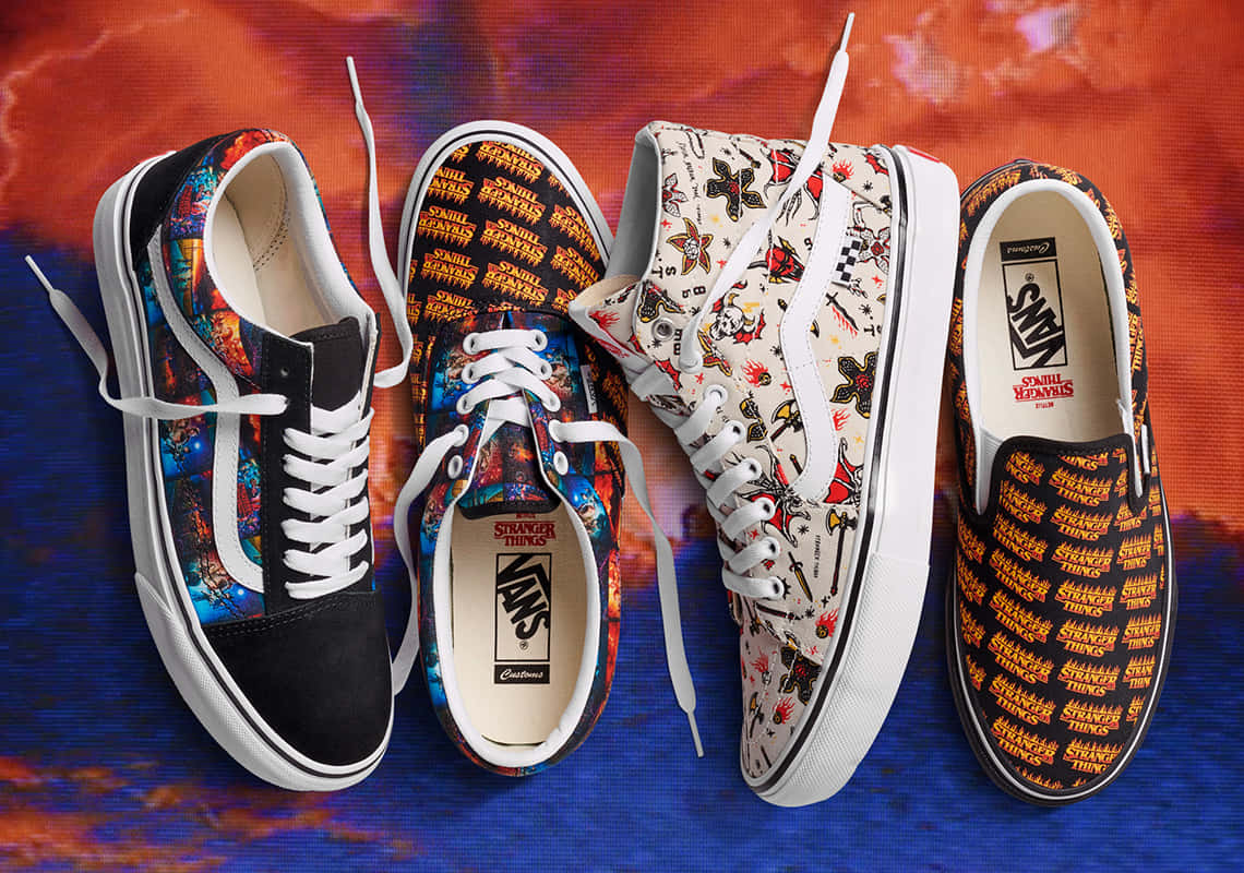 Vans 桌布 壁紙 — 四雙以《怪奇物語》為主題的Vans運動鞋，帶有鮮豔的圖案印花，展示在火熱的橙色和藍色漸變背景前。