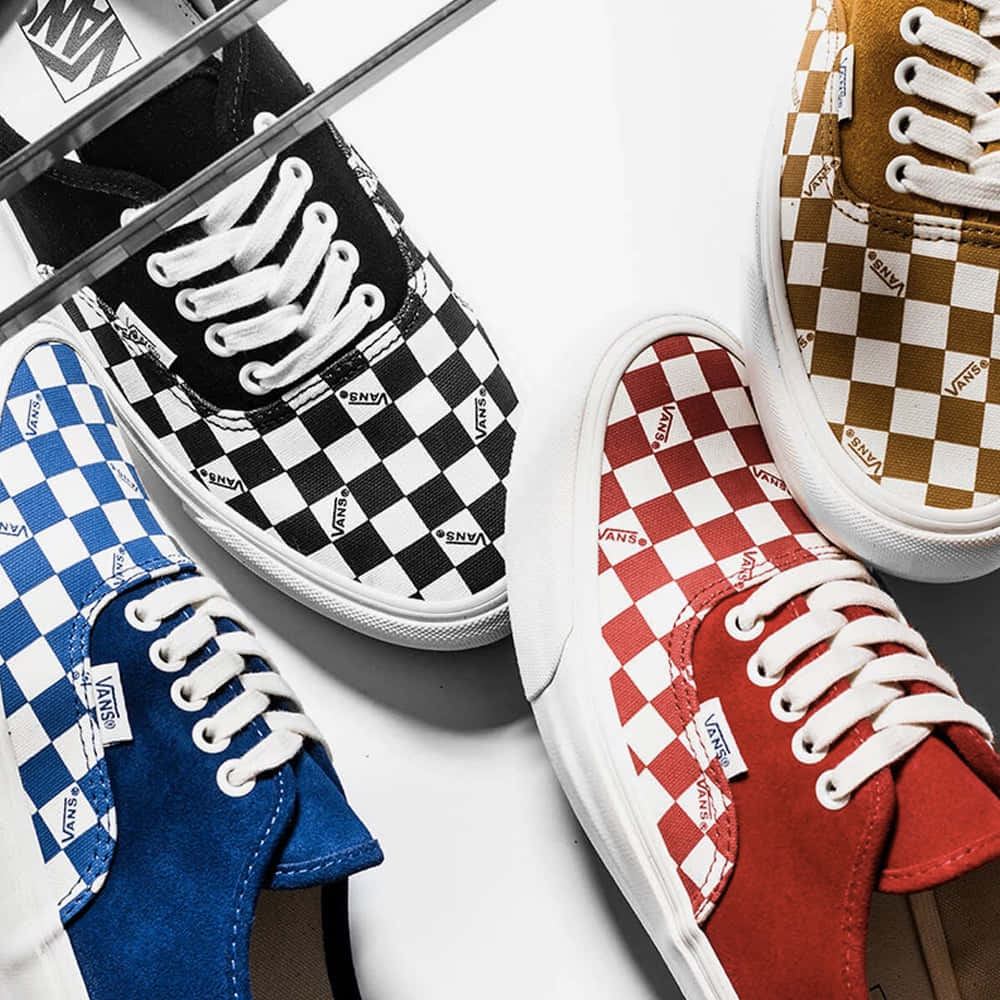Vans 桌布 壁紙 — 四雙色彩繽紛的Vans格紋圖案運動鞋，對角排列在潔白的表面上。