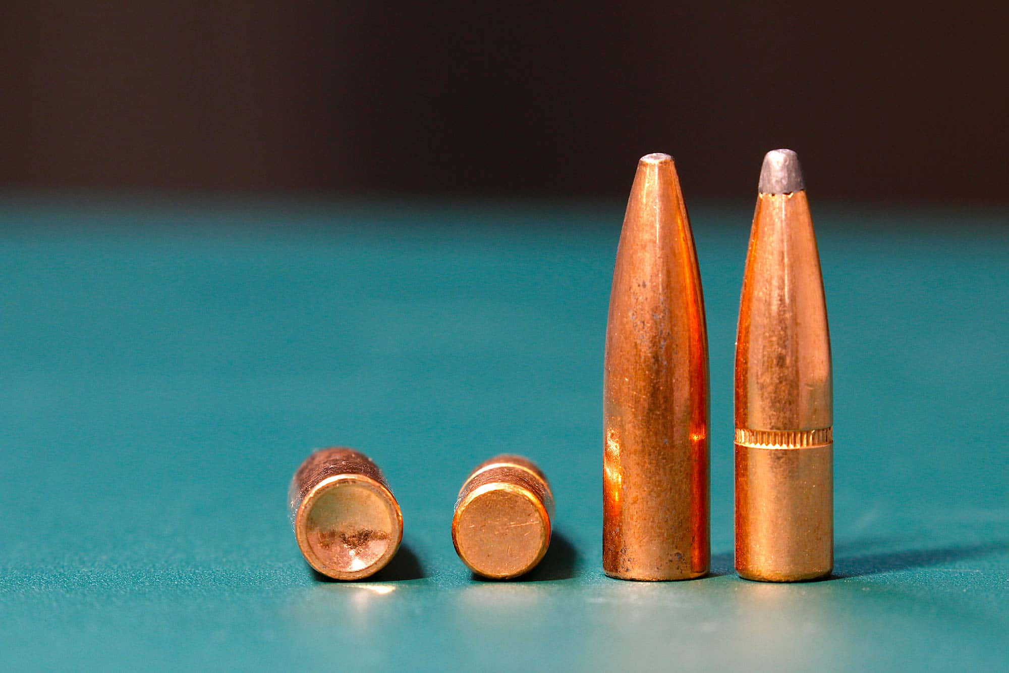 bullet 桌布 壁紙 — 四顆大小不一的銅殼子彈排列在青綠色表面上，景深較淺。