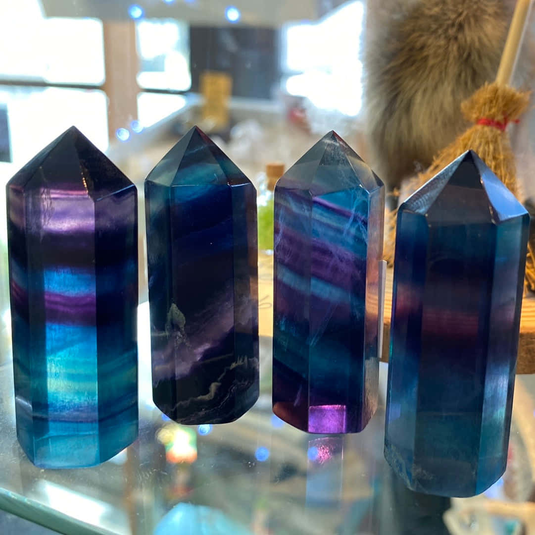 水晶 桌布 壁紙 — 四顆拋光螢石晶體尖端帶有鮮豔的藍色和紫色條紋，排列在反光玻璃表面上。
