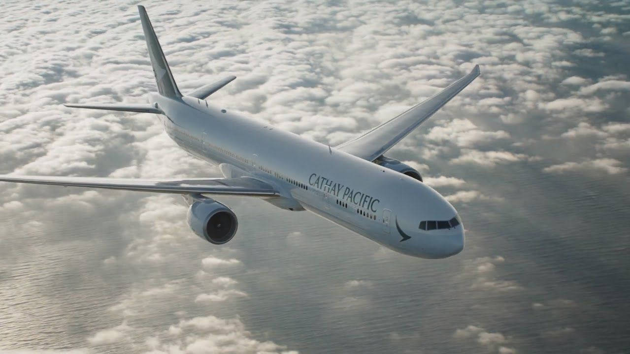 飛機 桌布 壁紙 — 國泰航空飛機在柔和日光下，優雅地翱翔於廣闊的蓬鬆白雲之上。