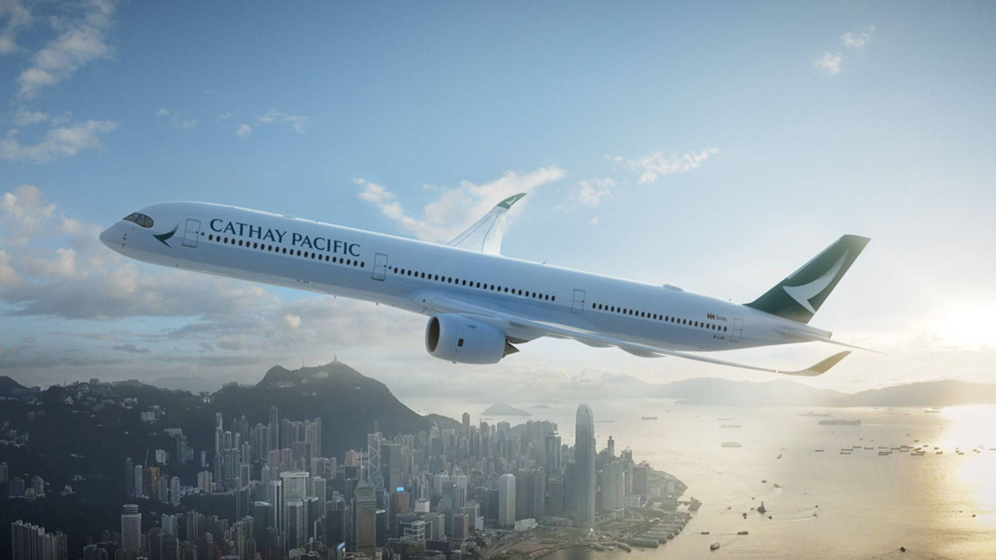 飛機 桌布 壁紙 — 國泰航空飛機在黃金時段翱翔於香港天際線之上，下方有陽光普照的雲層和港口。