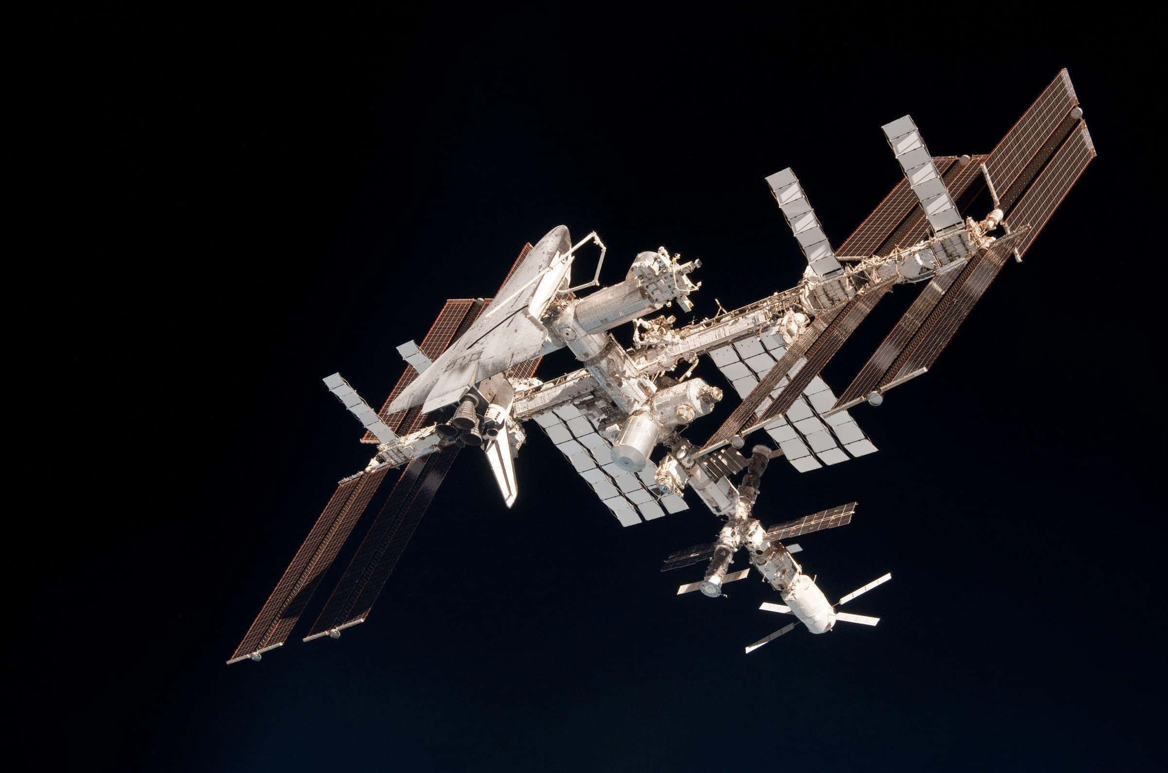 Iss 桌布 壁紙 — 國際太空站在深邃太空的漆黑背景下，閃耀著複雜的金屬細節。