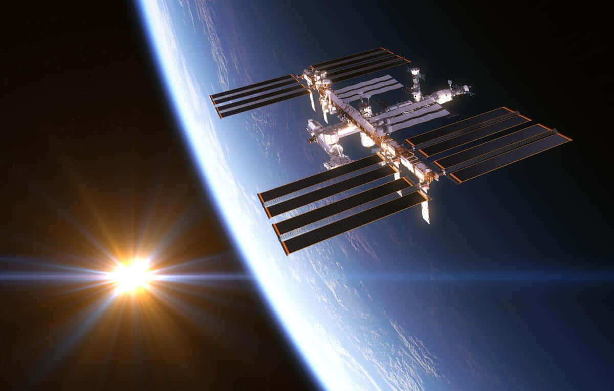 International Space Station 桌布 壁紙 — 國際太空站繞地球運行，太陽光輝映襯藍色行星曲線。