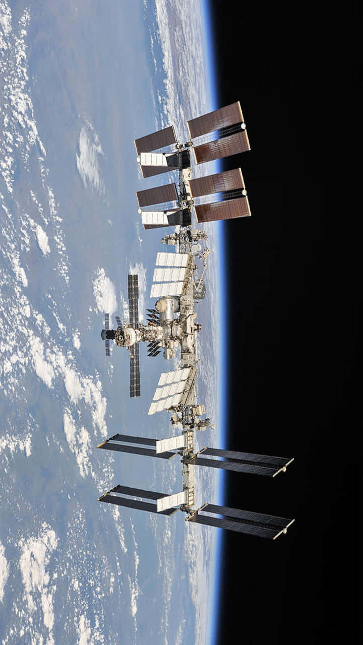Space Technology 桌布 壁紙 — 國際太空站繞地球運行，太陽能板在太空的漆黑中展開。