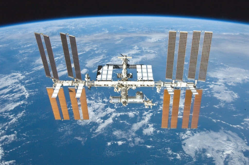 International Space Station 桌布 壁紙 — 國際太空站繞地球運行，顯示太陽能板及下方的藍色星球。