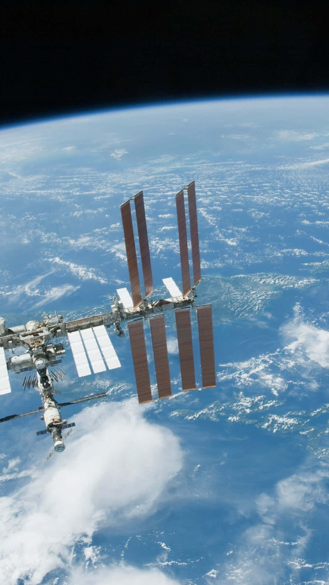 Iss 桌布 壁紙 — 國際太空站繞地球運行，顯示藍色海洋、白色雲層和彎曲的地平線，背景是黑色太空。