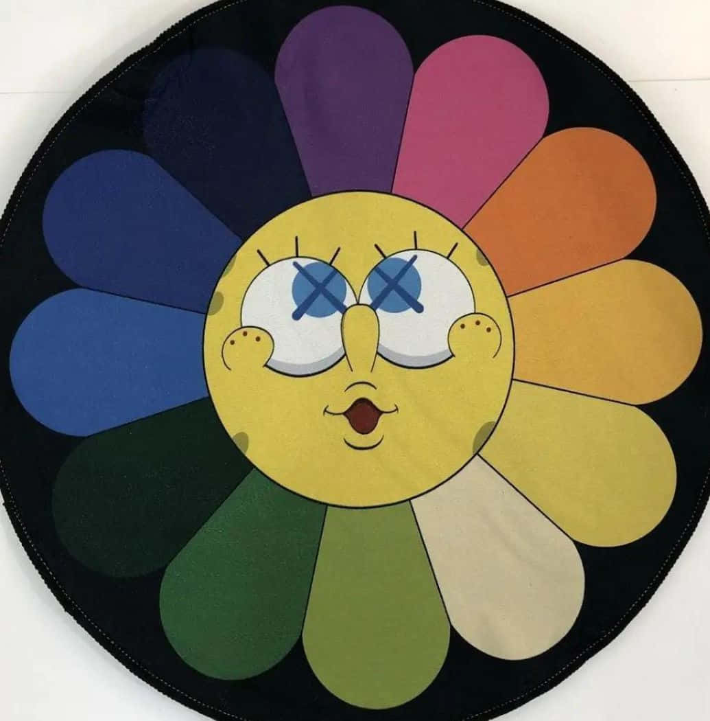 Kaws Spongebob 桌布 壁紙 — 圓形地毯上有一個快樂的黃色卡通臉，帶有X形眼睛，周圍環繞著彩虹色的花瓣，背景為黑色。