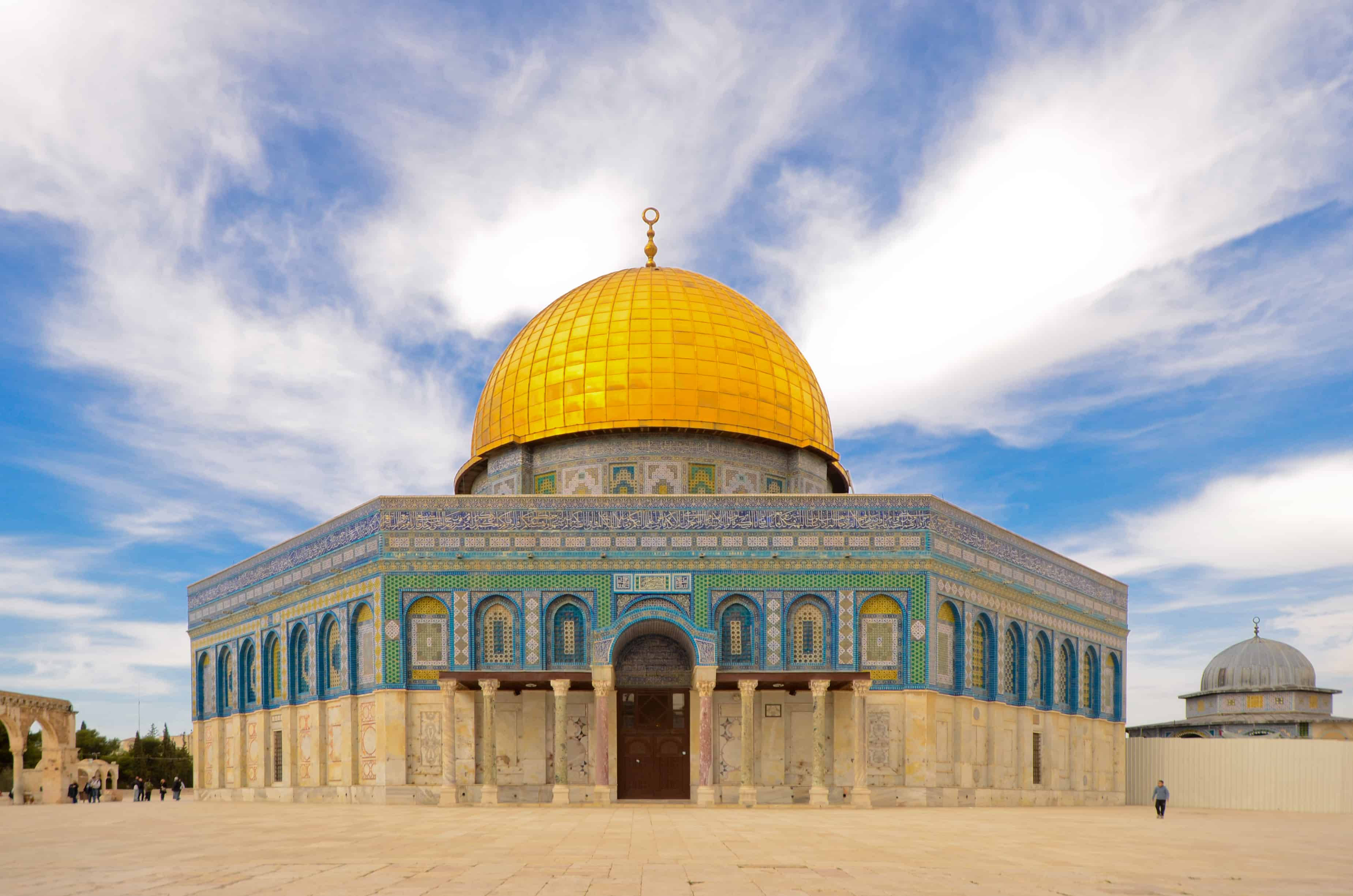 Israel 桌布 壁紙 — 圓頂清真寺在明亮藍天和縷縷白雲下閃耀金光，其精緻的藍綠色瓷磚外牆巍然聳立。