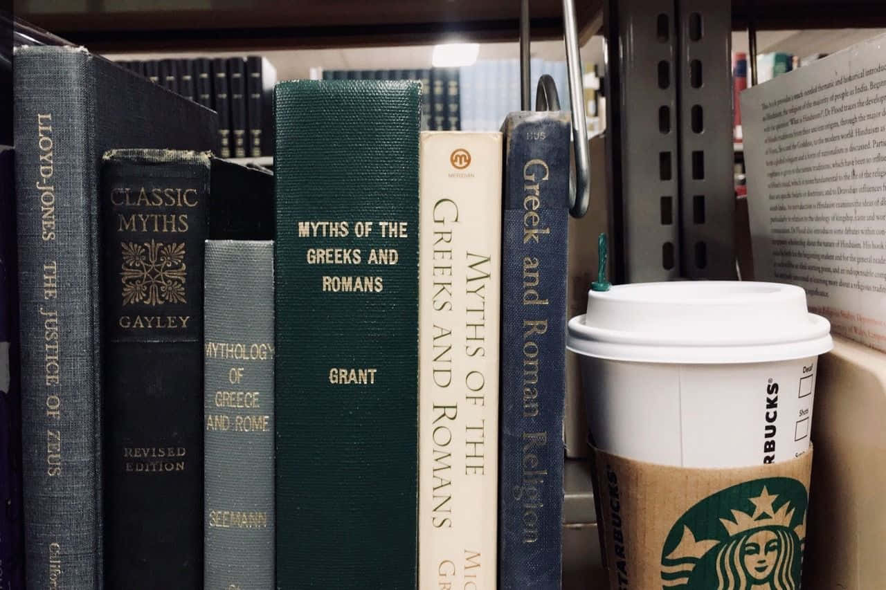 Dark Academia Aesthetic 桌布 壁紙 — 圖書館書架上的復古神話書與星巴克咖啡杯的特寫。