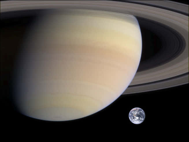 Ringed Planet 桌布 壁紙 — 土星以其標誌性的環主導畫面，一顆小小的藍色地球在廣闊的太空黑暗中漂浮在附近。