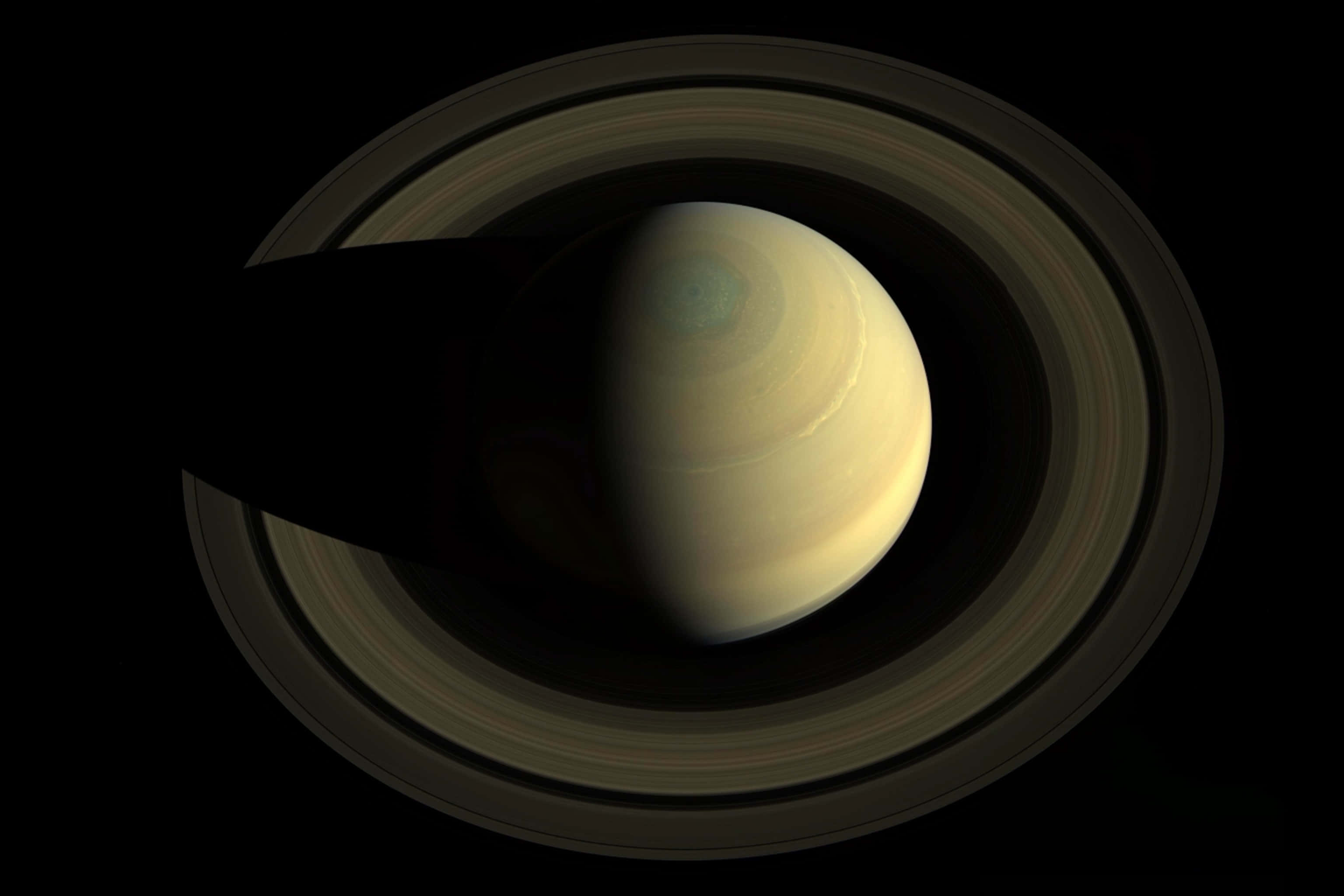 土星 桌布 壁紙 — 土星在虛空中柔和地發光，其標誌性的環在其表面投下長長的陰影。