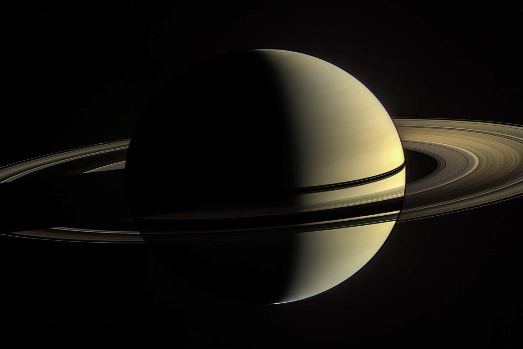 土星 桌布 壁紙 — 土星在虛空中柔和發光，其標誌性光環在宇宙黑暗中投下銳利陰影。