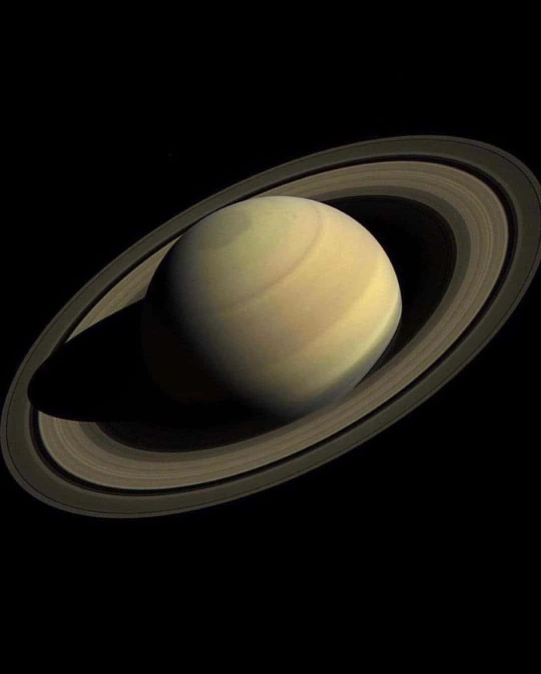 土星 桌布 壁紙 — 土星在虛空中柔和發光，其標誌性環在深空中投下銳利陰影。