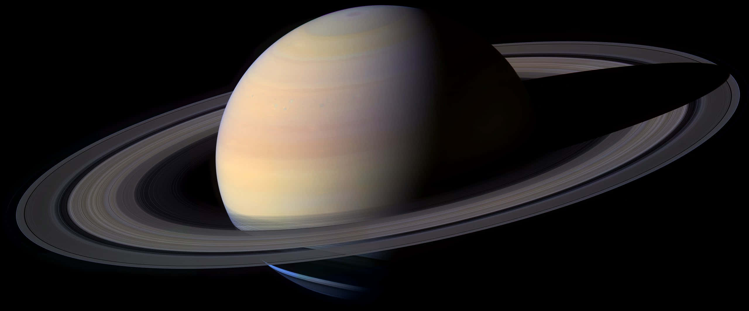 High Quality 桌布 壁紙 — 土星在黑色太空中柔和發光，其標誌性環在其條紋大氣層上投下銳利的陰影。