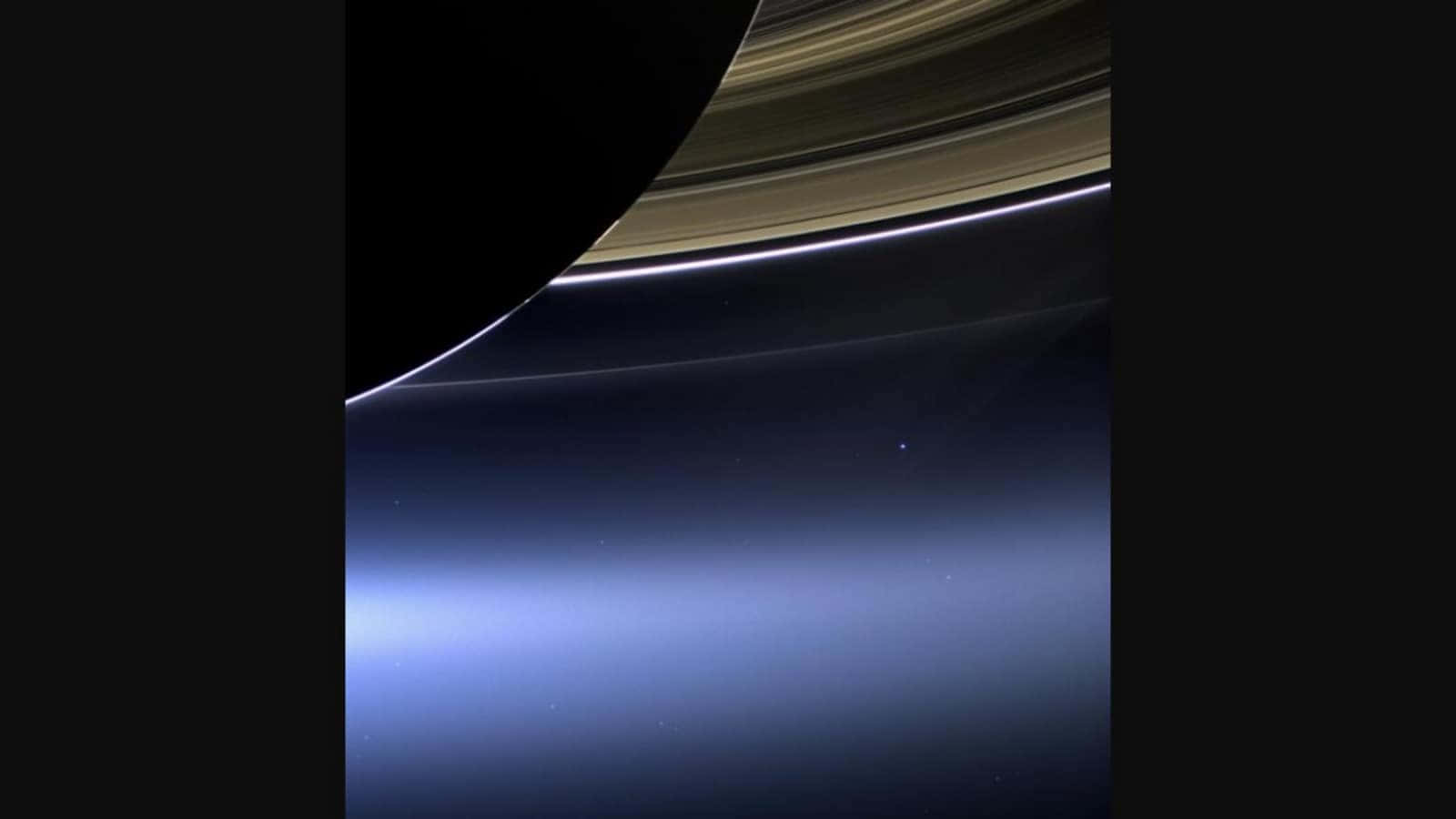 土星 桌布 壁紙 — 土星環在黑暗太空虛空中發光，下方帶有微妙的藍色大氣薄霧，令人嘆為觀止。
