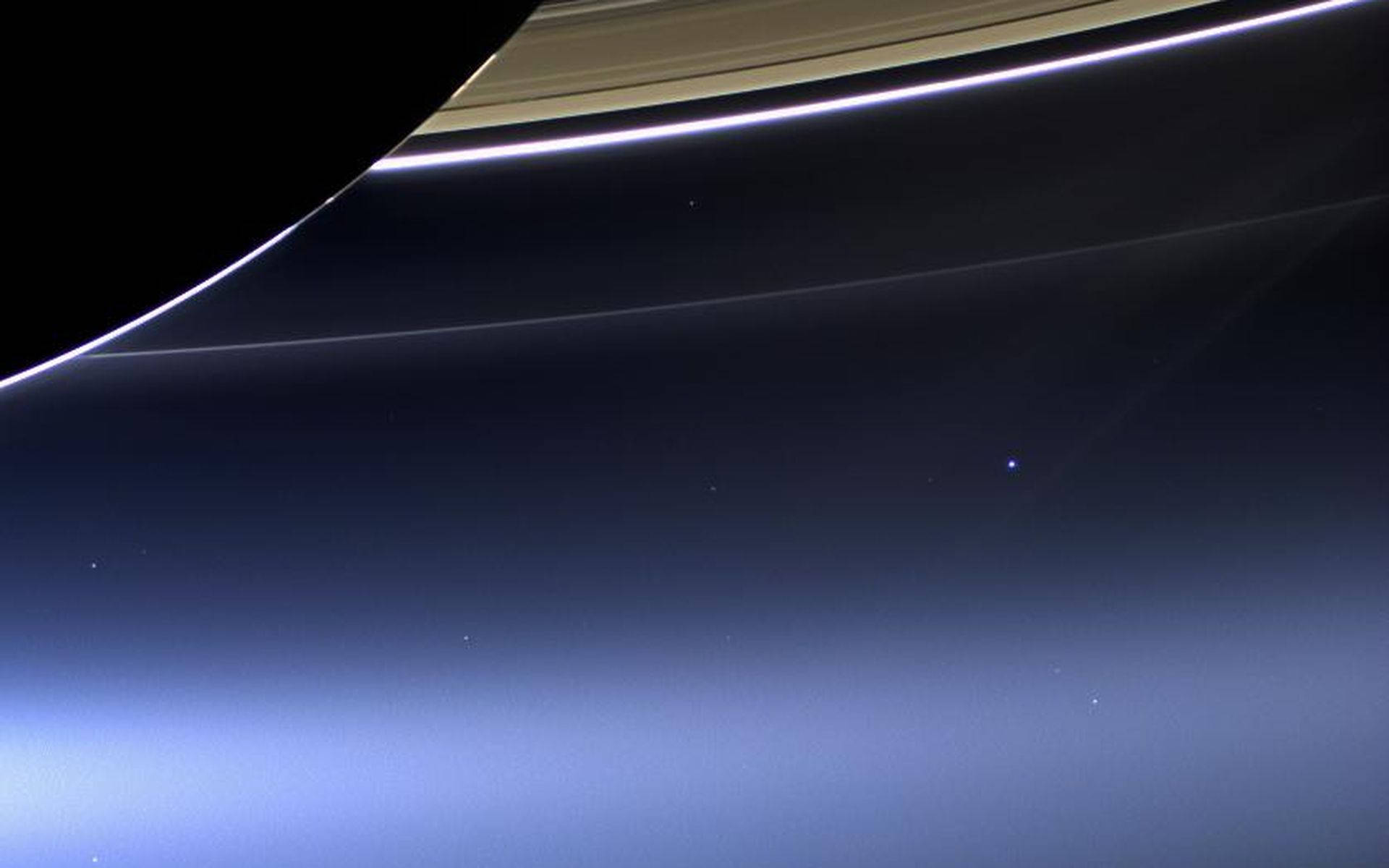 NASA 動態圖片 桌布 壁紙 — 土星環在黑暗太空虛空中發光的壯麗景色，下方有柔和的藍色大氣漸變。