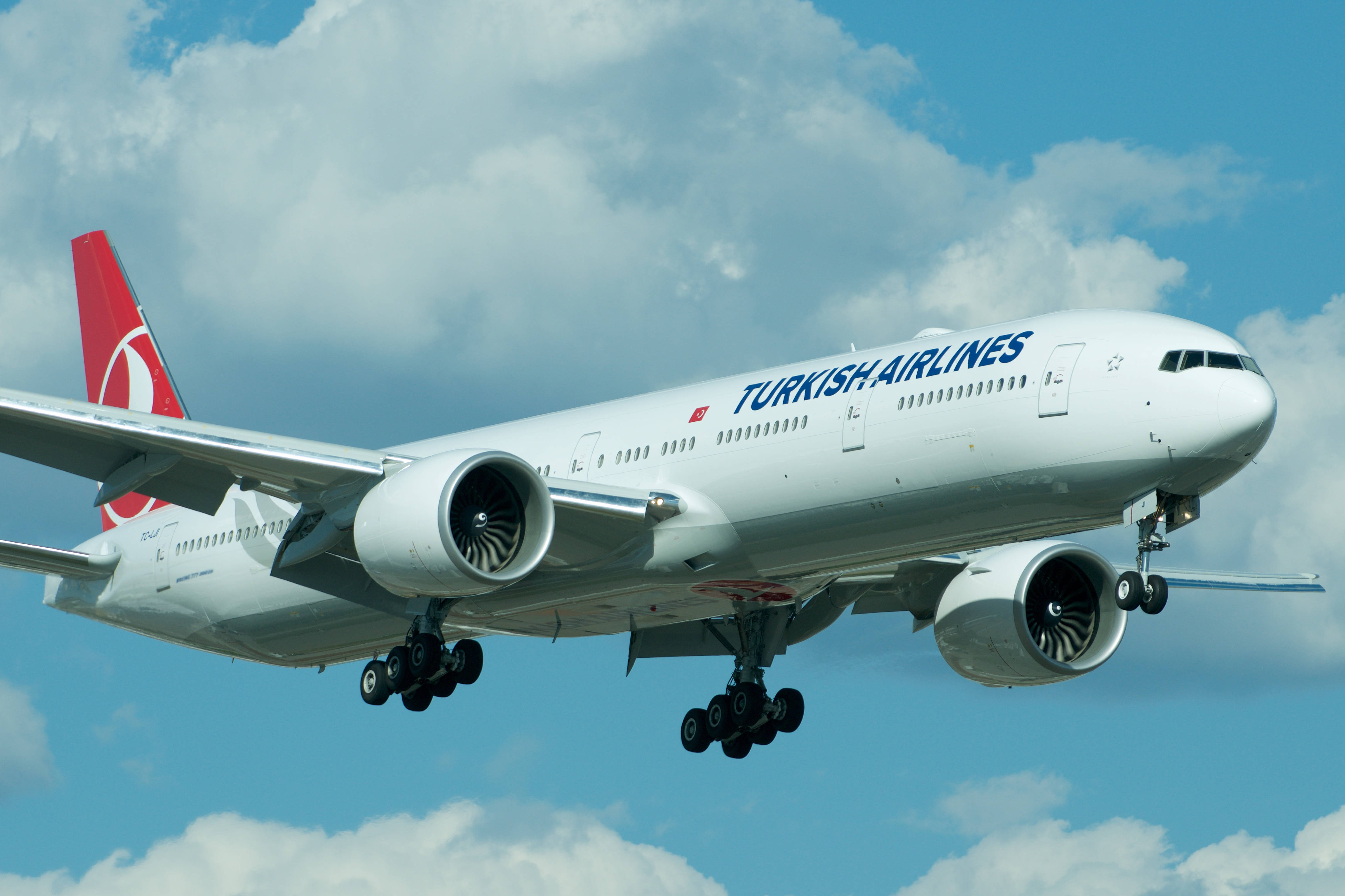 飛機 桌布 壁紙 — 土耳其航空波音777客機正在飛行，起落架放下，背景是充滿蓬鬆白雲的明亮藍天。
