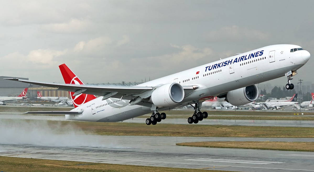 Airport 桌布 壁紙 — 土耳其航空波音777從濕滑跑道起飛，上空有雲，背景有其他飛機。