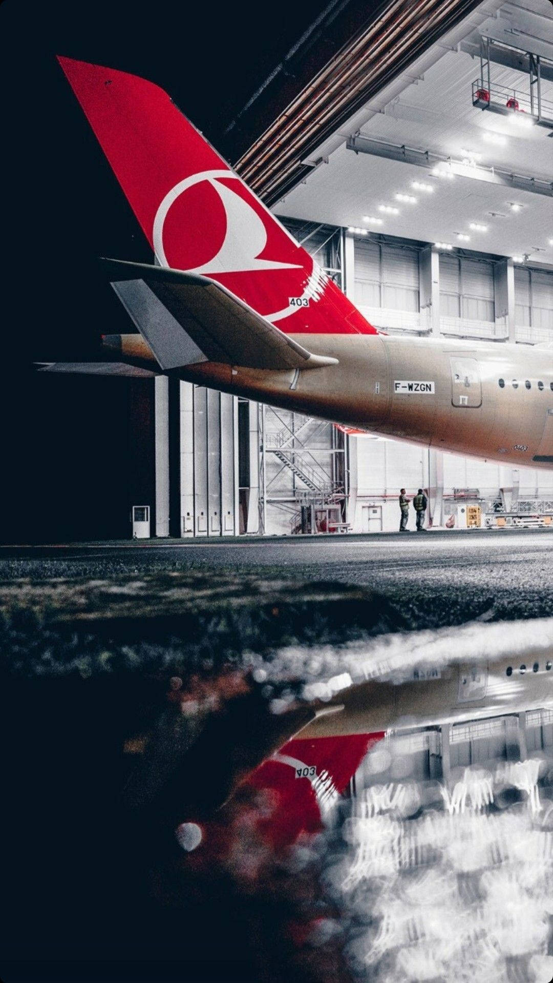 Airport 桌布 壁紙 — 土耳其航空飛機尾部倒映在昏暗機庫內的水坑中，附近有兩人站立。