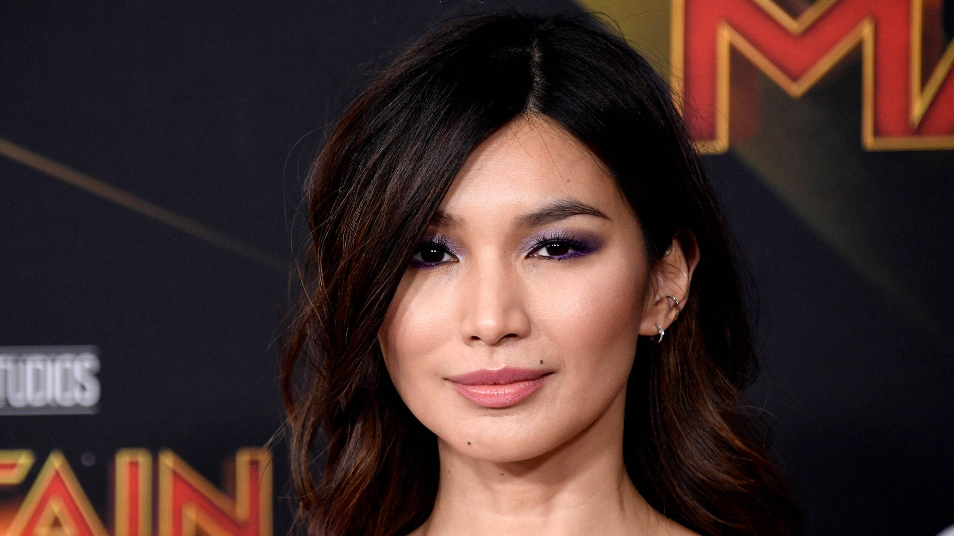 Gemma Chan 桌布 壁紙 — 在Marvel Studios活動中，一位深色頭髮和紫色眼影女性的特寫肖像。