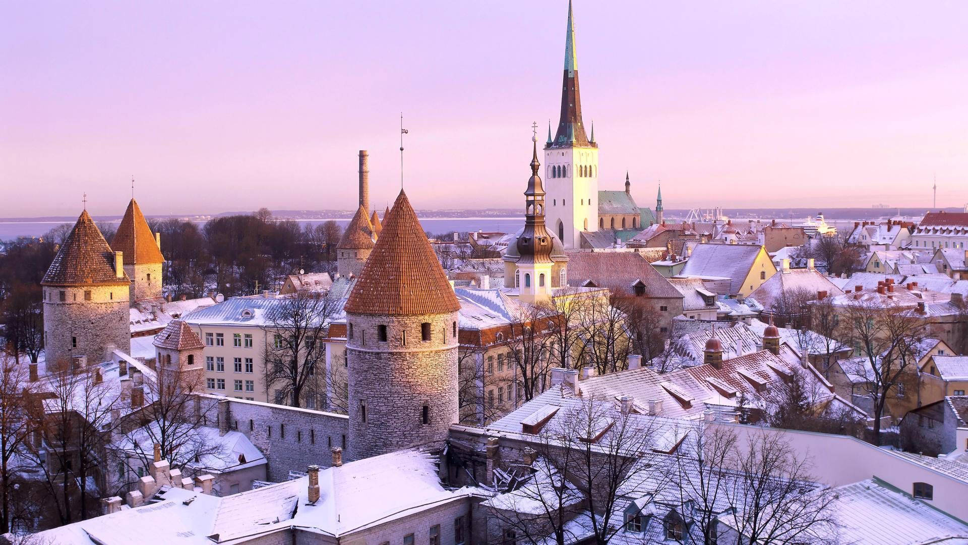 Estonia 桌布 壁紙 — 在一個中世紀的歐洲小鎮，柔和的紫色日出下，白雪覆蓋了歷史悠久的塔樓和屋頂。