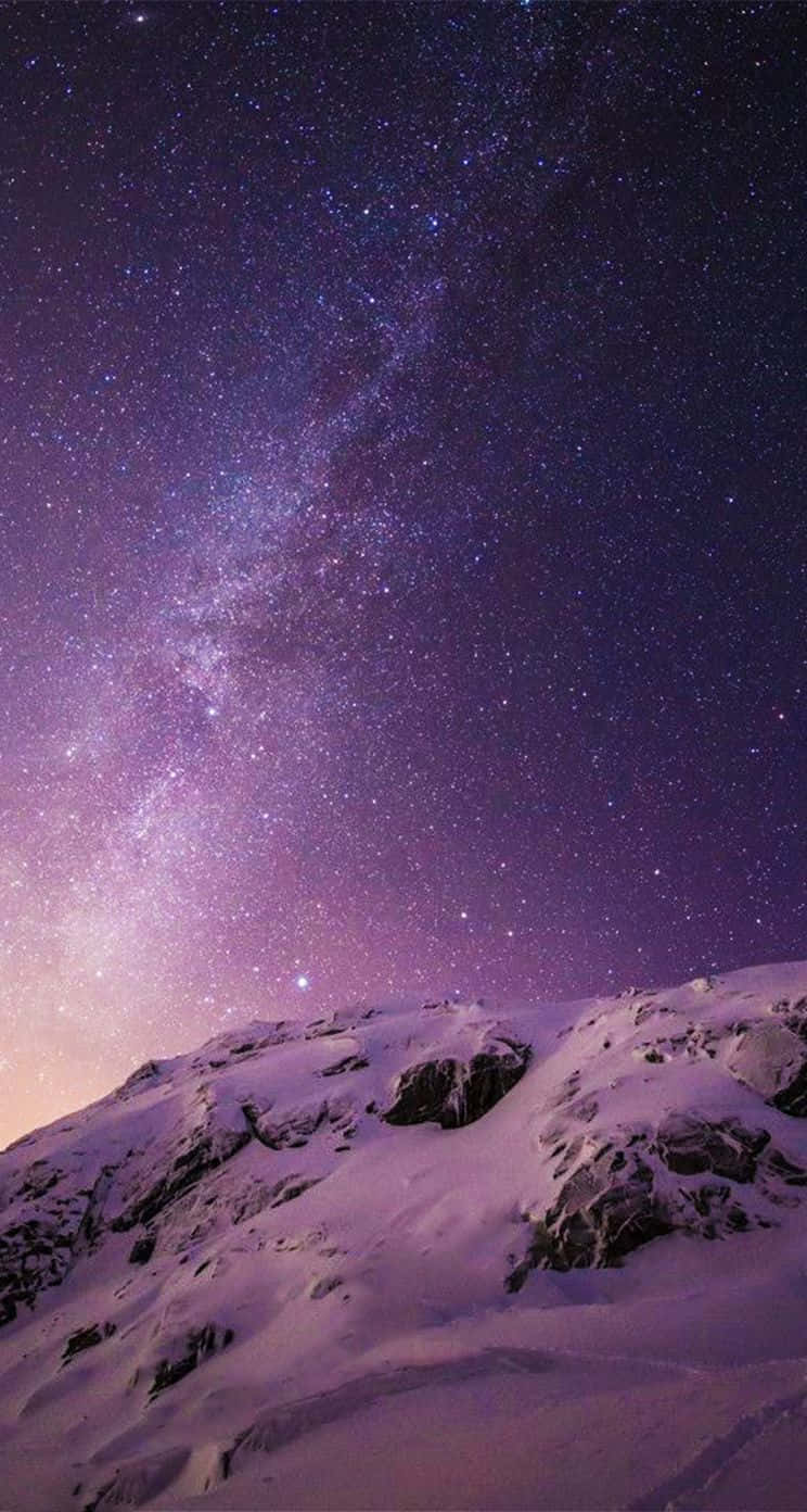 桌布 壁紙 — 在充滿銀河和無數星星的充滿活力的紫色夜空下的雪覆蓋的山脊。
