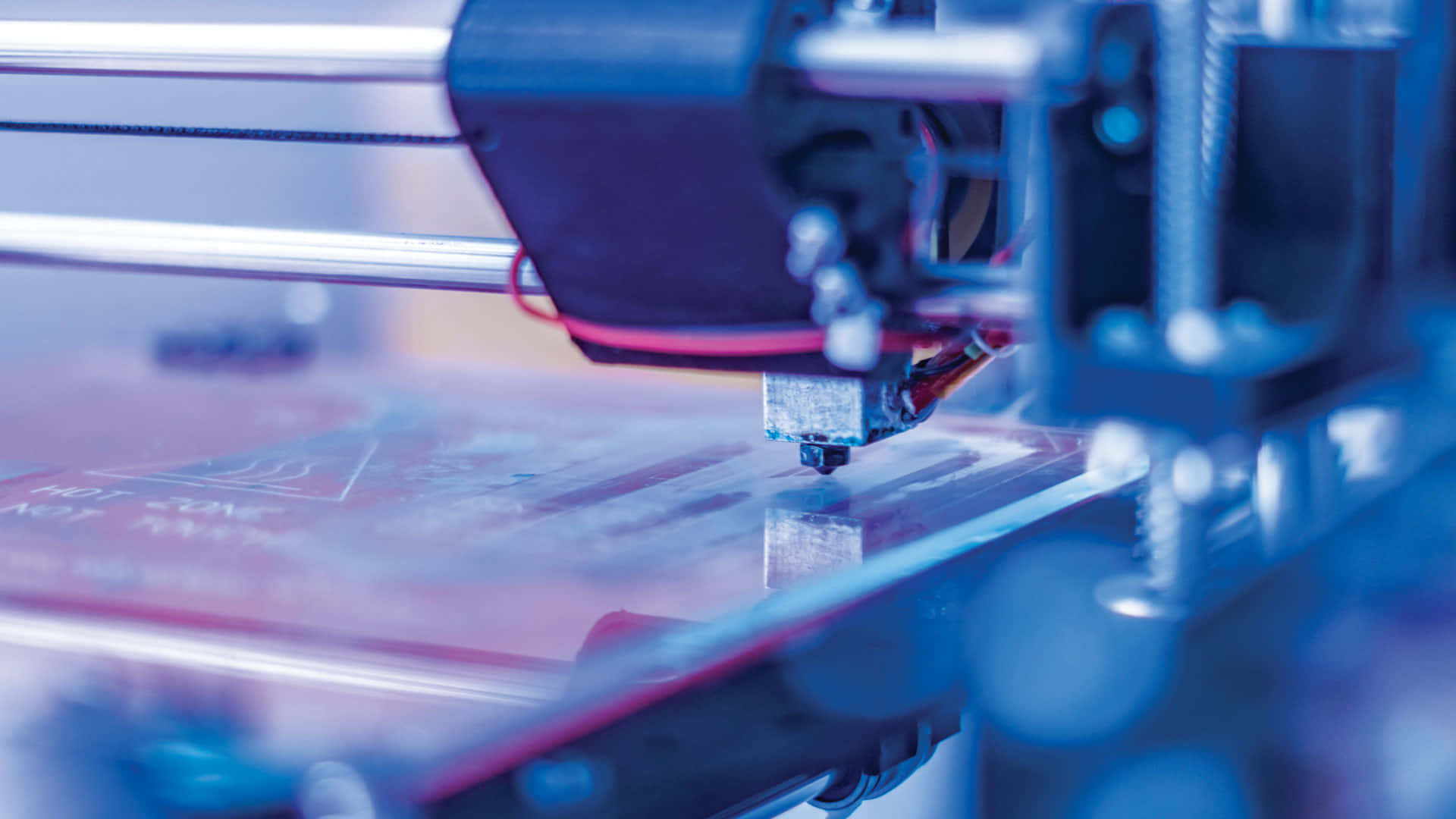 3d Printer 桌布 壁紙 — 在冷藍色燈光下，3D列印機將線材擠出到列印平台上的特寫。