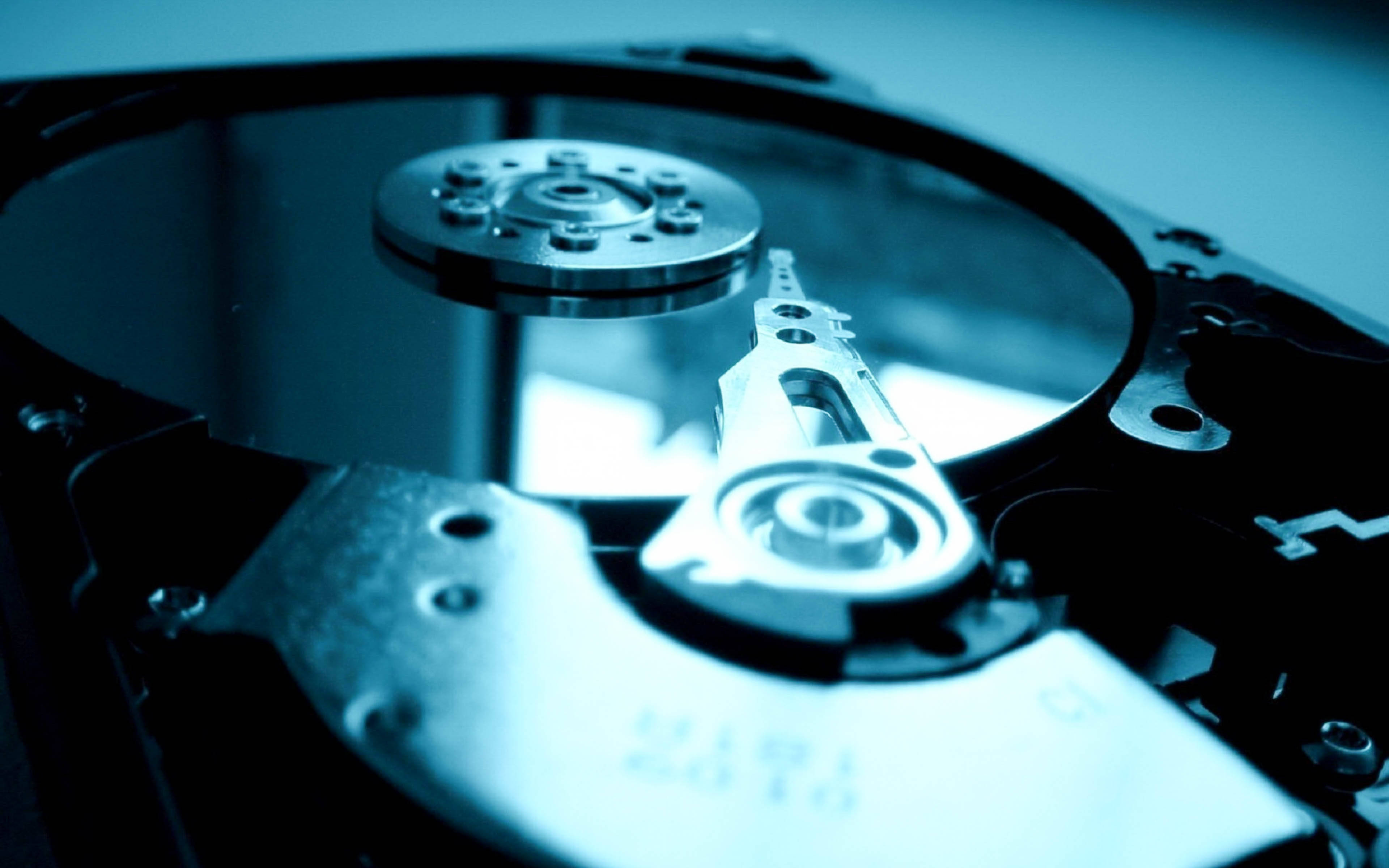 Hard Drive 桌布 壁紙 — 在冷藍色燈光下，打開的硬碟特寫，顯示金屬碟片和讀寫頭。