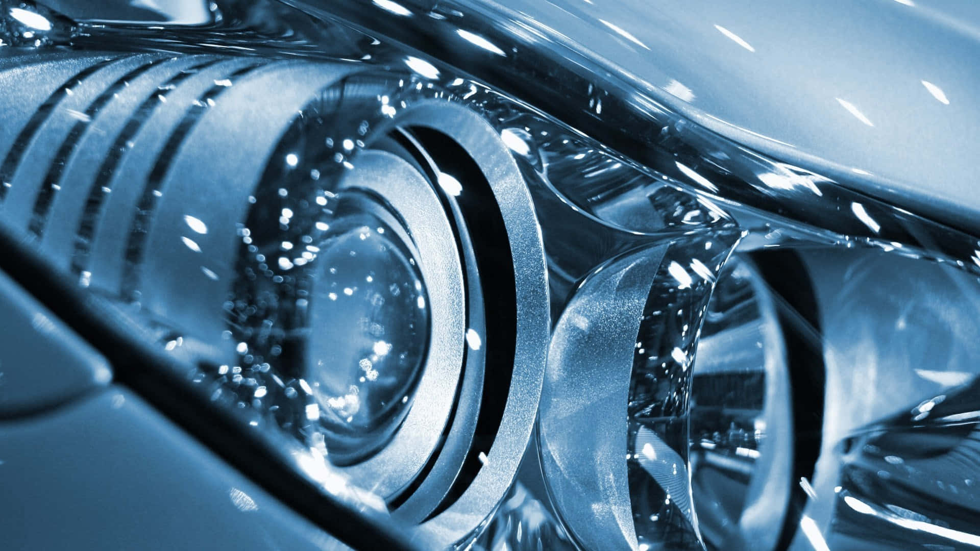 Mechanical Engineering 桌布 壁紙 — 在冷藍色燈光下，時尚車頭燈的特寫，帶有複雜的圓形圖案和反光鍍鉻表面。