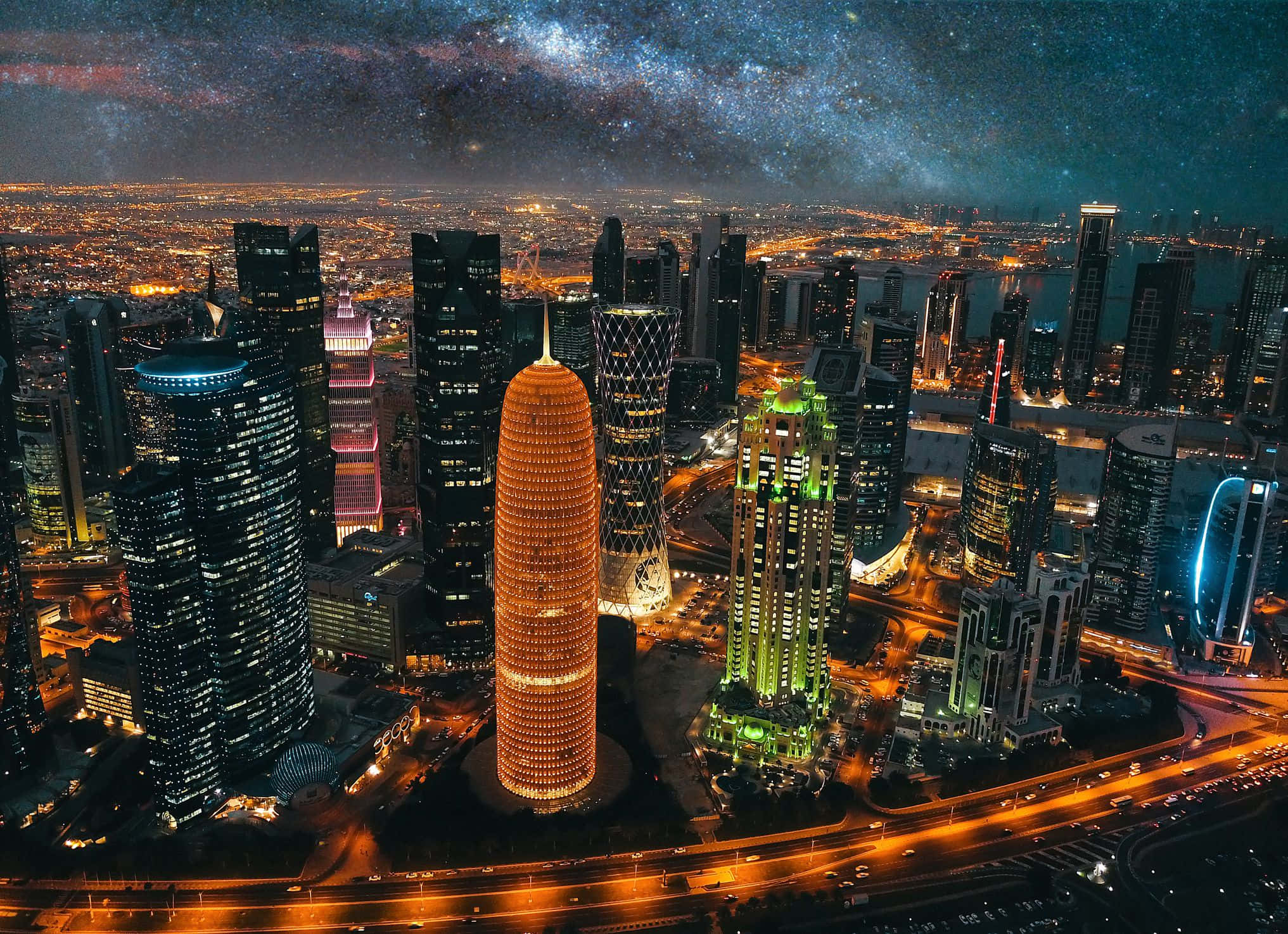 卡達 桌布 壁紙 — 在可見銀河系的充滿活力的星空下，未來主義摩天大樓的耀眼夜景。