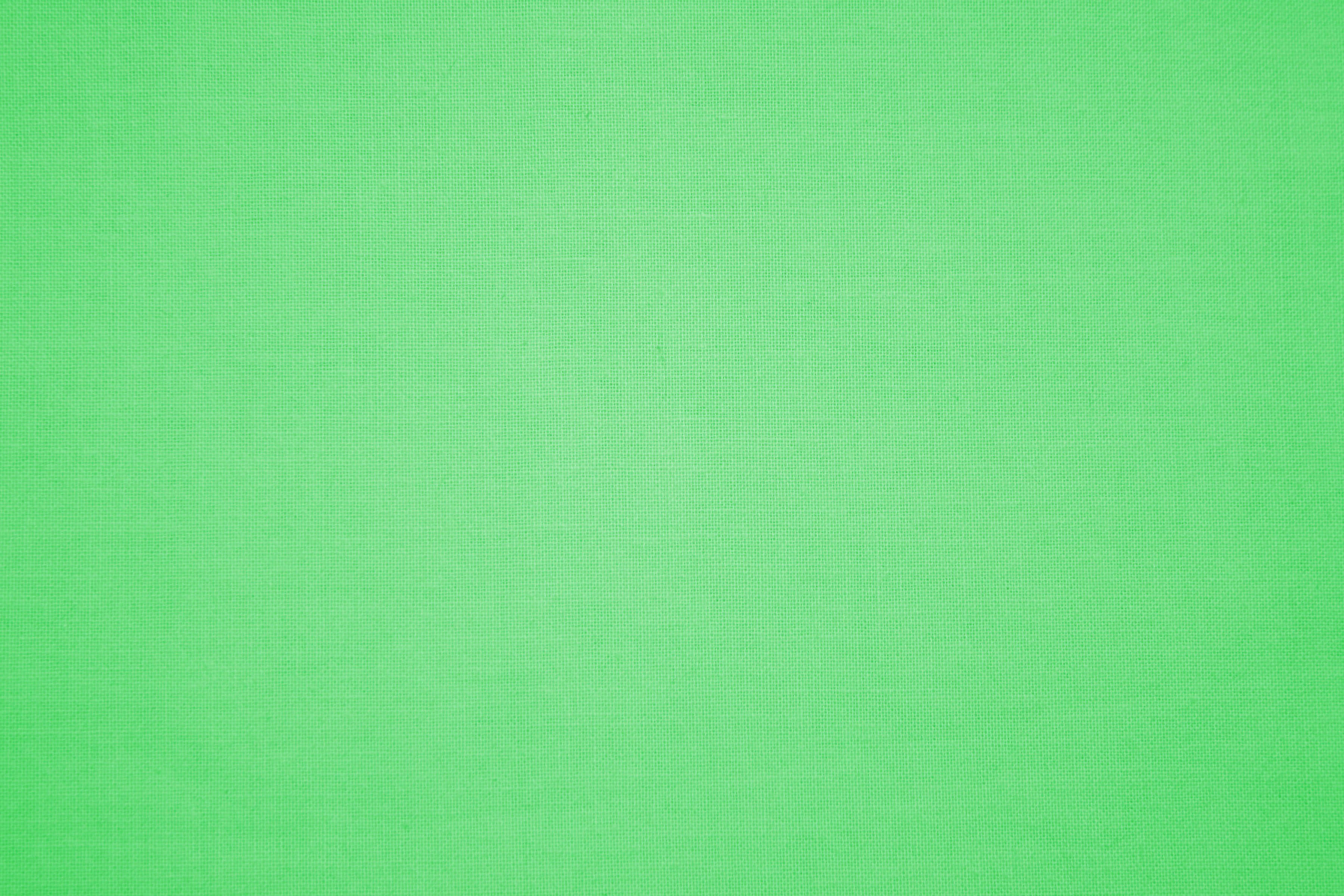 Green Texture 桌布 壁紙 — 在均勻光線下，帶有細微編織紋理的平滑純綠色布料表面。