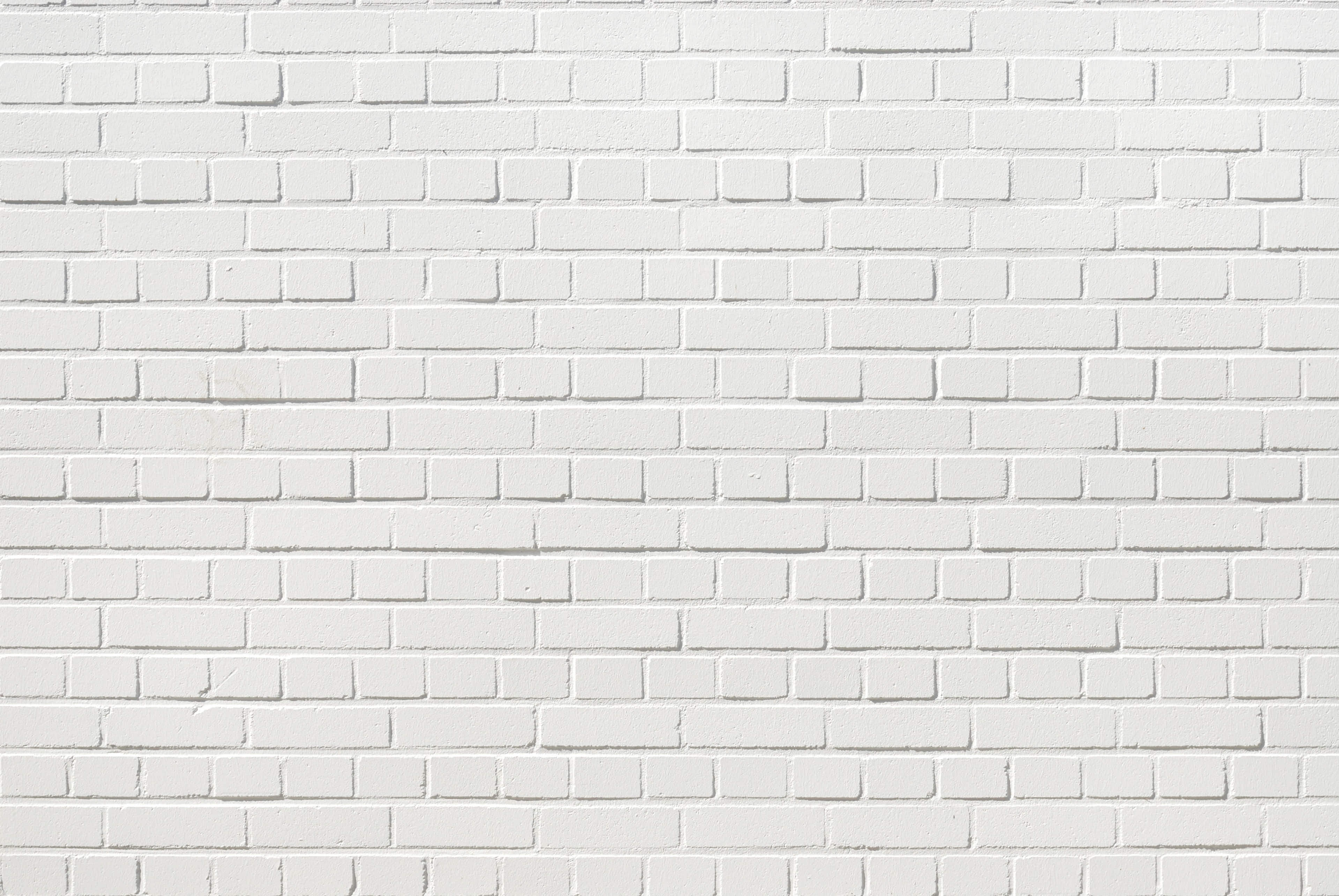 Brick Wall 桌布 壁紙 — 在均勻照明下，帶有細微紋理和砂漿線的清潔白色磚牆。