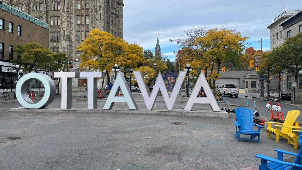 Attraction 桌布 壁紙 — 在多雲的天空下，城市廣場上的大型銀色「OTTAWA」字母被秋天樹木和色彩繽紛的椅子環繞。