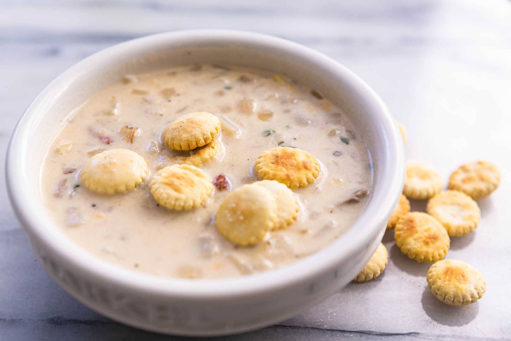 Chowder 桌布 壁紙 — 在大理石表面上，一碗奶油蛤蜊濃湯配上金色牡蠣餅乾。