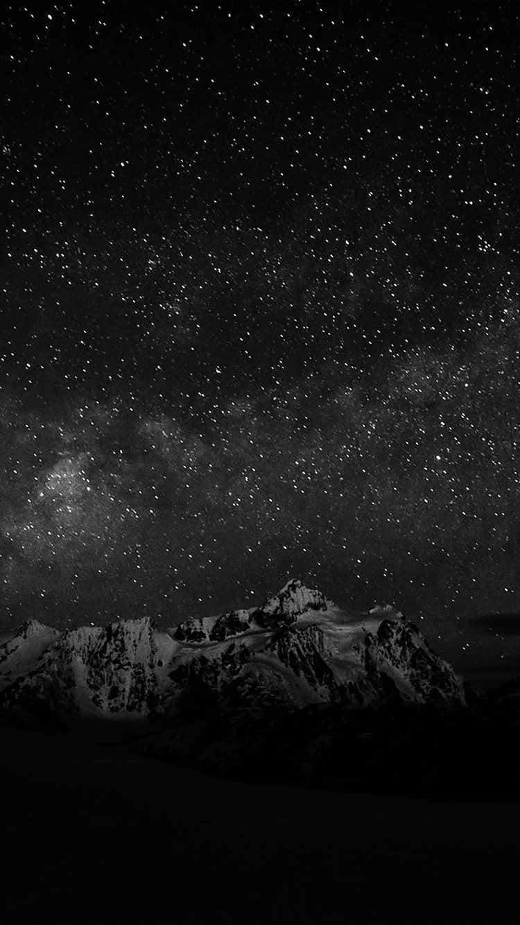 Stars 桌布 壁紙 — 在密集星場和銀河拱橋下的雪頂山脈單色景觀。