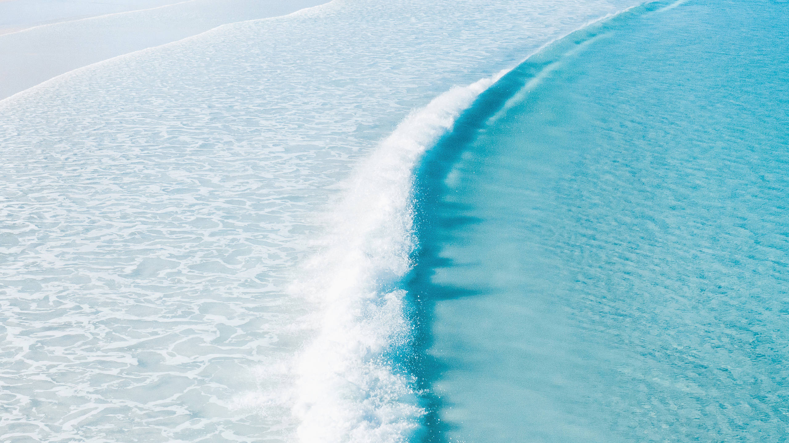Wave 桌布 壁紙 — 在寧靜的海岸場景中，一道平靜的海浪優雅地捲起，碧綠色的海洋與白色的浪花交匯。