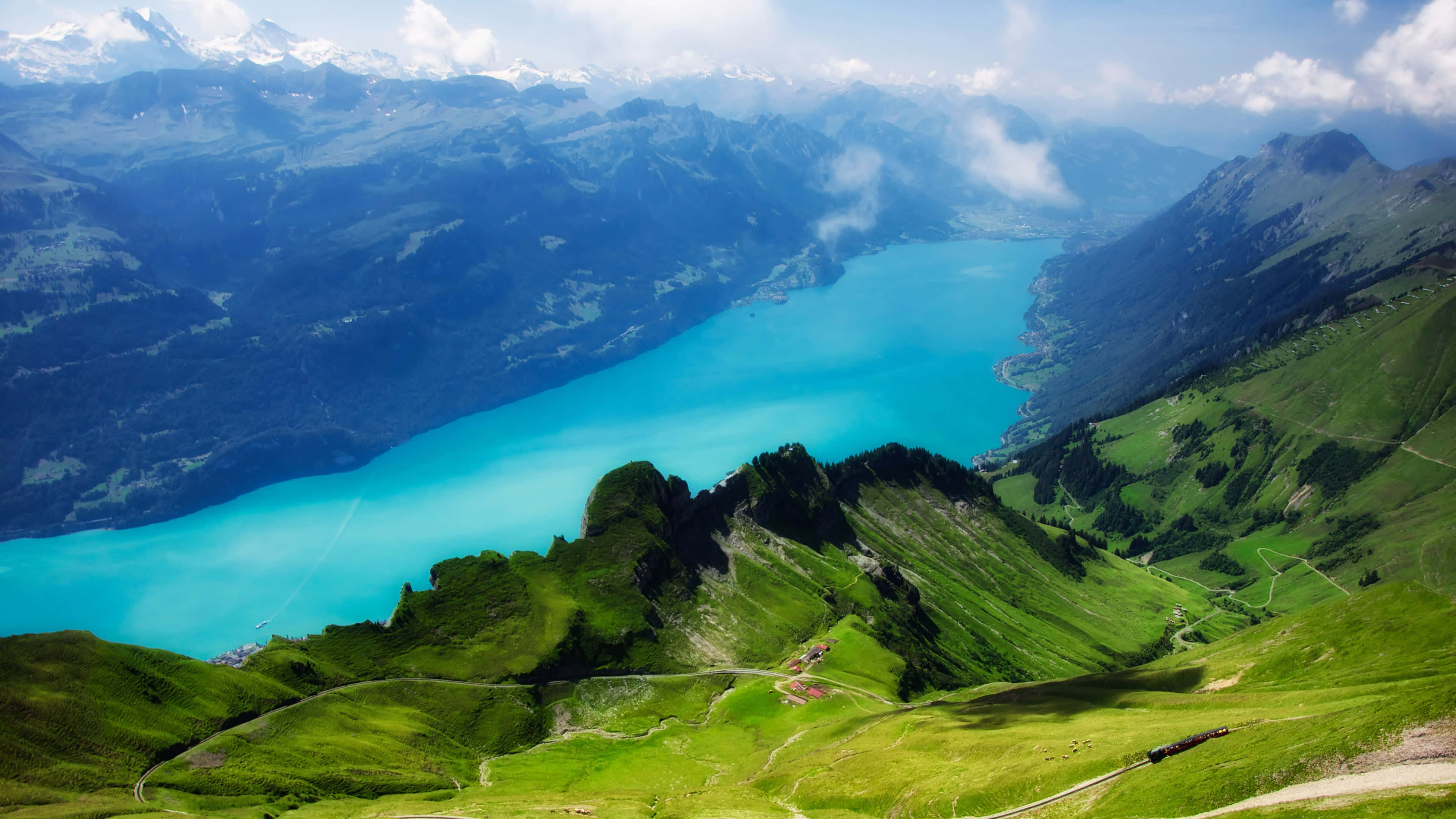 4K Ultra HD Landscape 桌布 壁紙 — 在局部多雲的天空下，一個碧綠的湖泊坐落於茂密的綠色山脈之間，令人嘆為觀止的航拍景色。