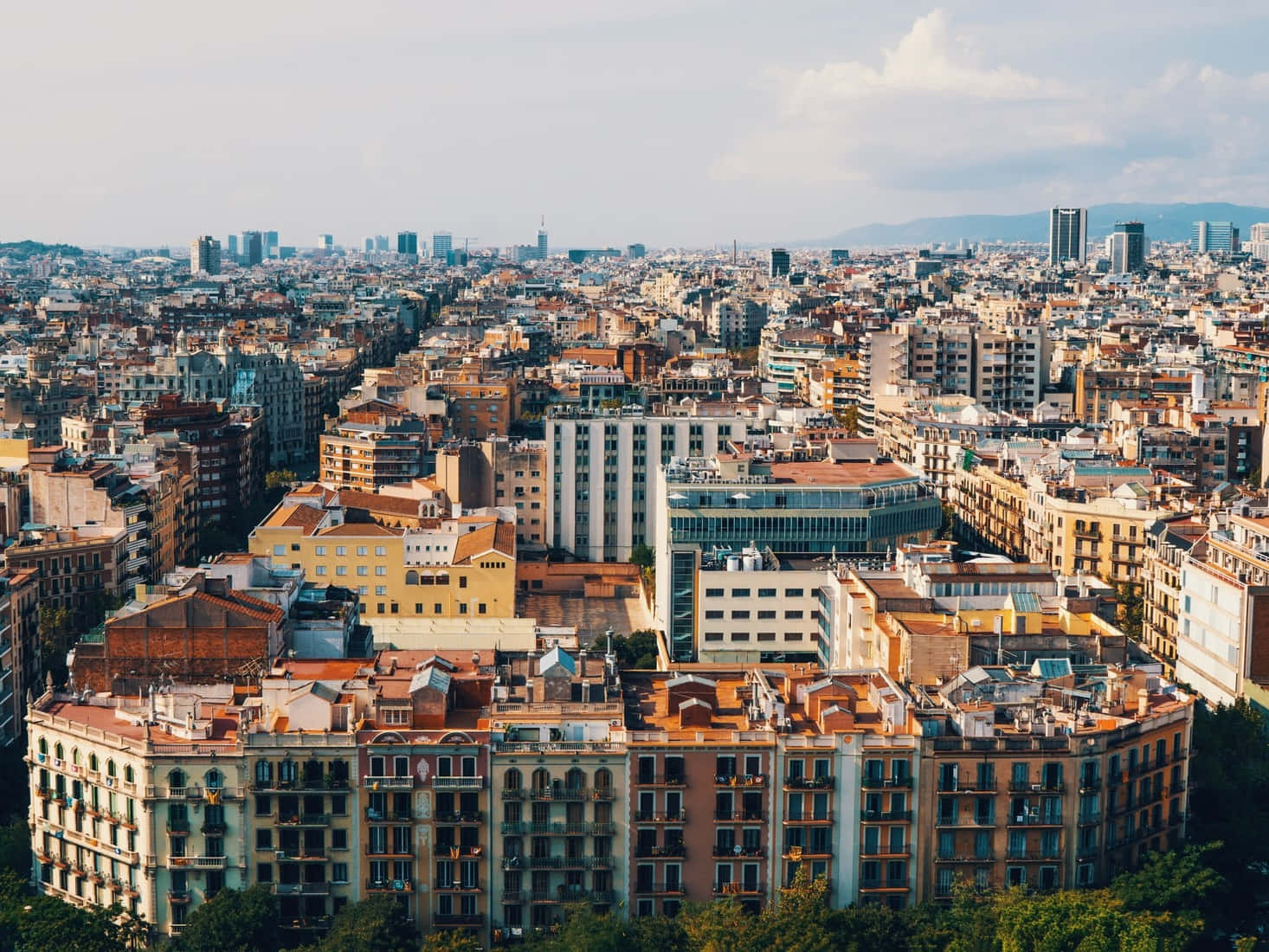 Barcelona 桌布 壁紙 — 在局部多雲的天空下，密集的歐洲城市景觀，擁有陶土屋頂和現代摩天大樓的鳥瞰圖。