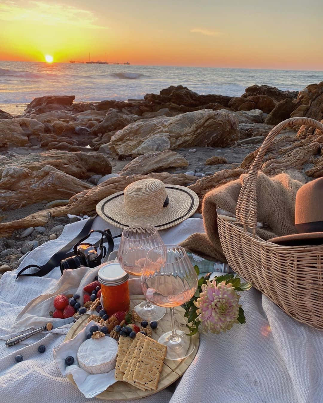 Beach Picnic 桌布 壁紙 — 在岩石海灘上享用美酒、起司和莓果的浪漫海邊日落野餐。