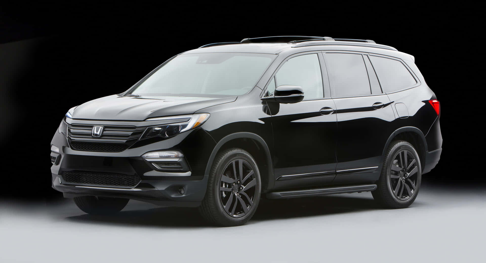 Honda Pilot 桌布 壁紙 — 在工作室中展示的時尚黑色本田Pilot SUV，配有戲劇性燈光和深色漸變背景。