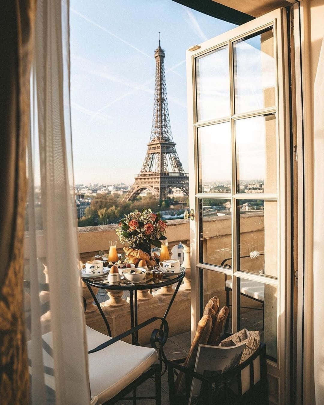 Eiffel Tower 桌布 壁紙 — 在巴黎陽台上享用早餐，新鮮法式長棍麵包和柳橙汁，俯瞰藍天白雲下的艾菲爾鐵塔。